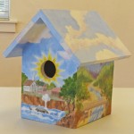The birdhouse painted by a local artist (artist's name not given).